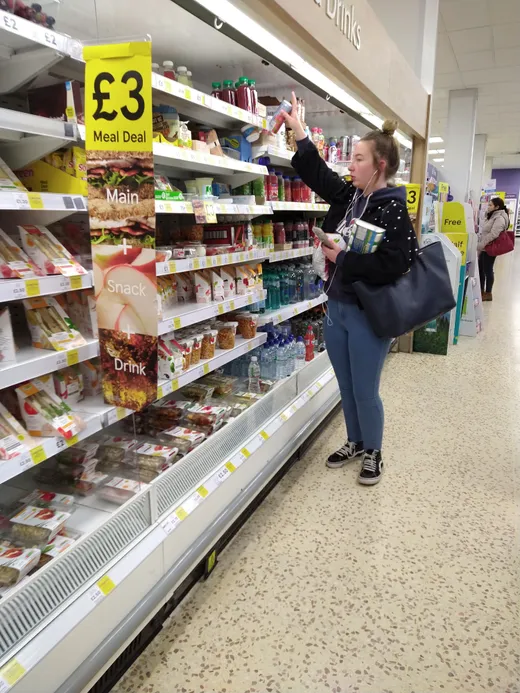 A supermarket shelf of packaged sandwiches, with a printed sign above it advertising a meal deal.
